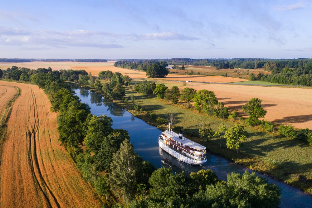 Kryssningsbåt åker på Göta Kanal i gyllene ljus
