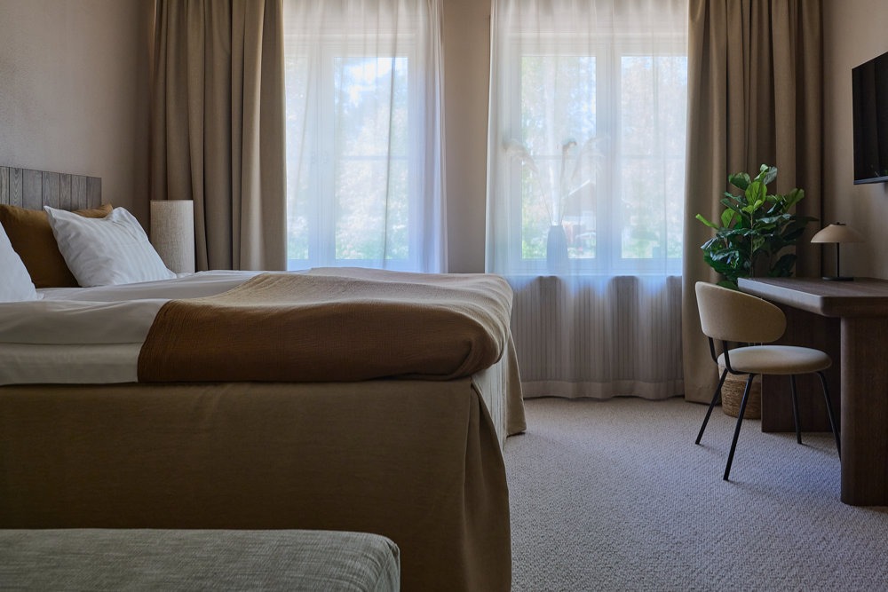 ljust hotellrum med skrivbord och fönster