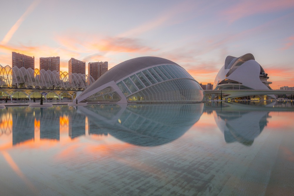 Konst- och vetenskapsstaden i Valencia med spegling i vatten vid solnedgång.
