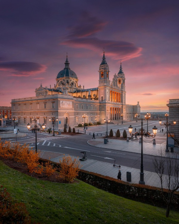 Almudena-katedralen i Madrid mot en dramatisk lila himmel vid solnedgång.